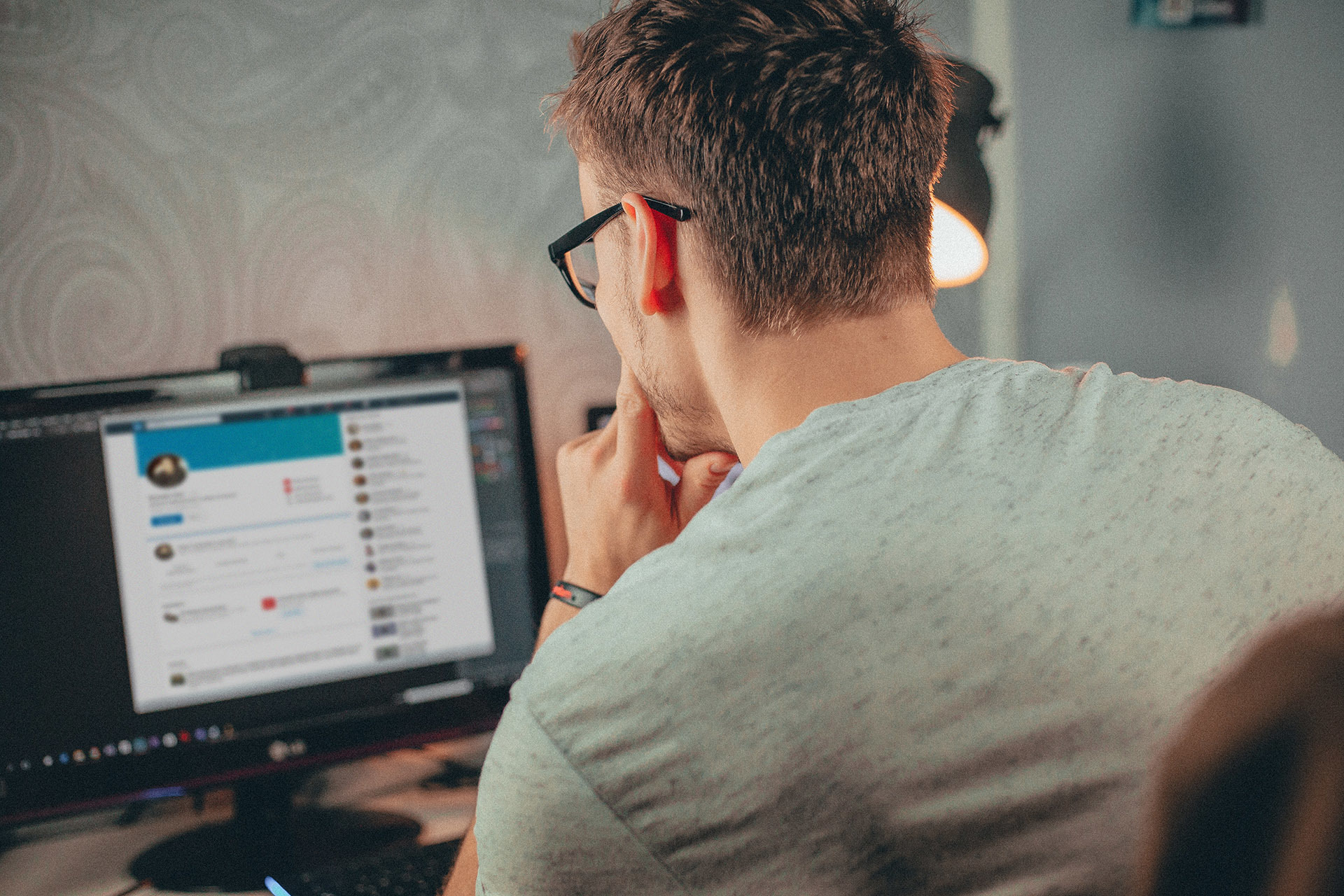 Man looking at social media profile on a computer screen.