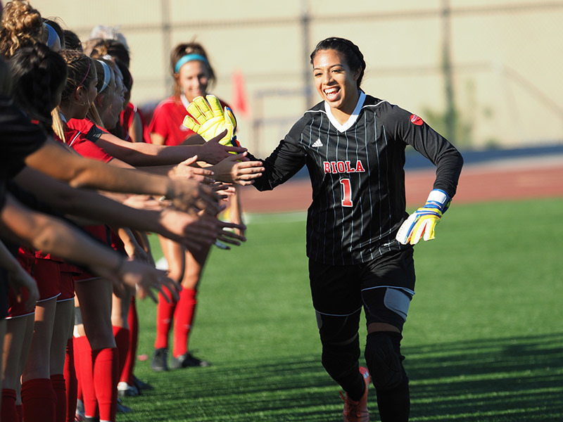 Photo of Biola goalkeeper giving high-fives to her teammates