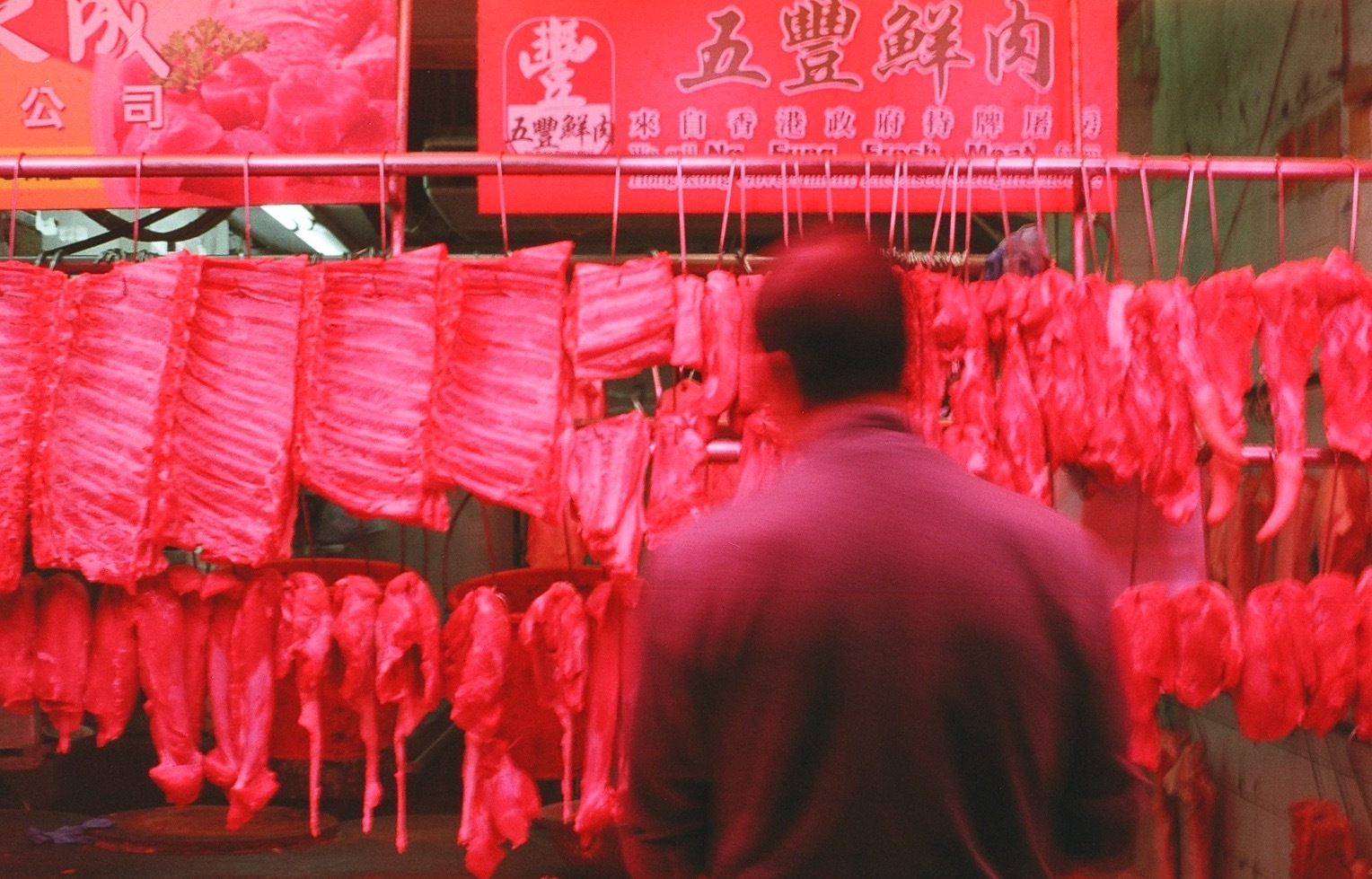 A film photo I captured in Hong Kong and included in my portfolio. It is of a man looking at hanging pieces of meat.