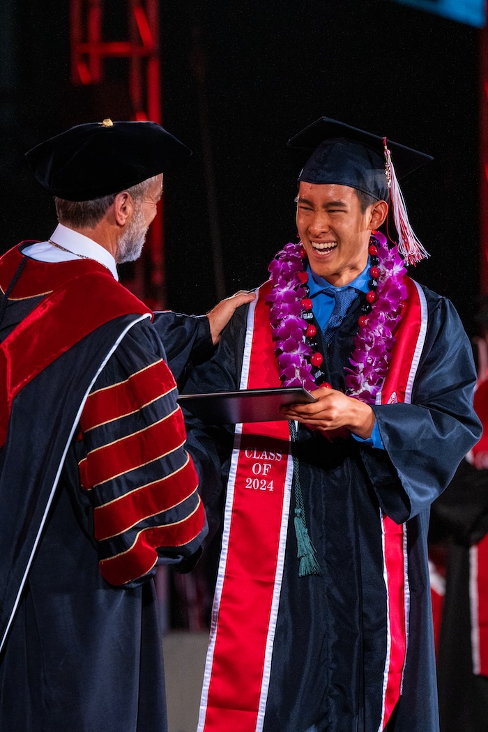Image shows a graduate receiving his degree from Dr. Corey