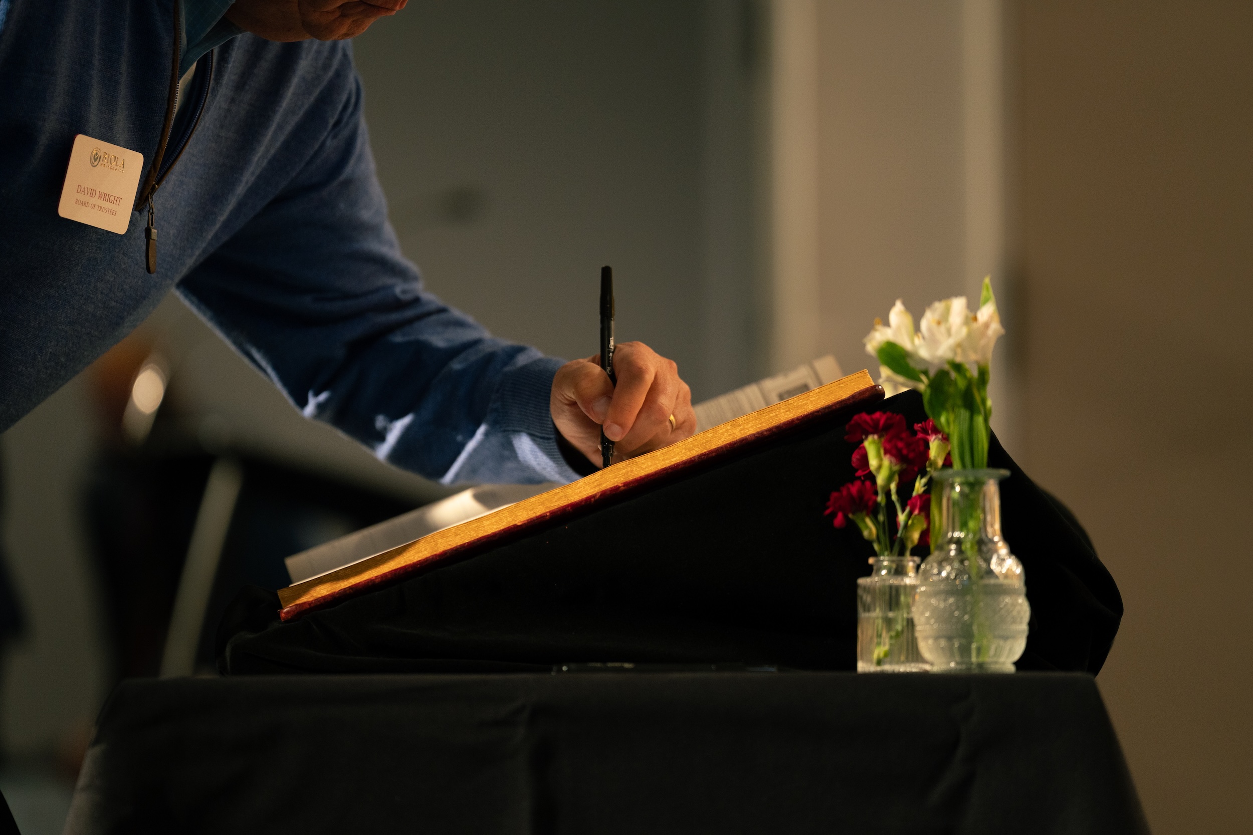 image shows a trustee member signing his name in the book