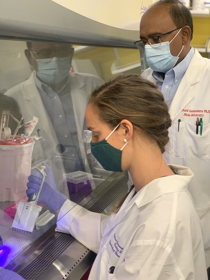 Image shows Katelyn Spradley is using a multichannel pipette for her research on antibiotics while Dr. Richard Gunasekera oversees her technique.