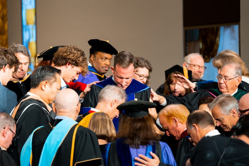 Image shows people praying over Dr. Matthew Hall