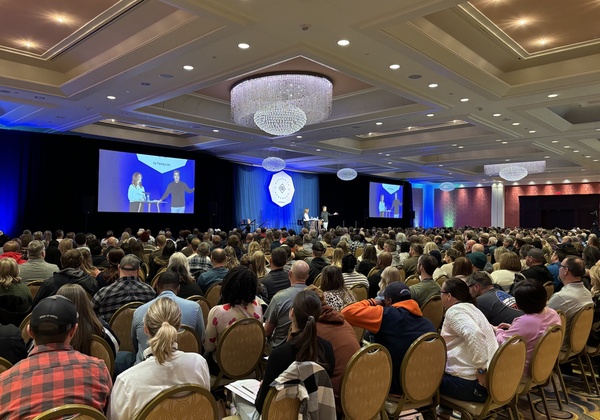 Chris and Alisa speaking in front of a large crowd at a conference