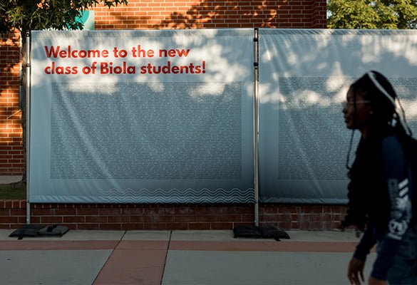 student walks by banner that welcomes the new class of Biola students