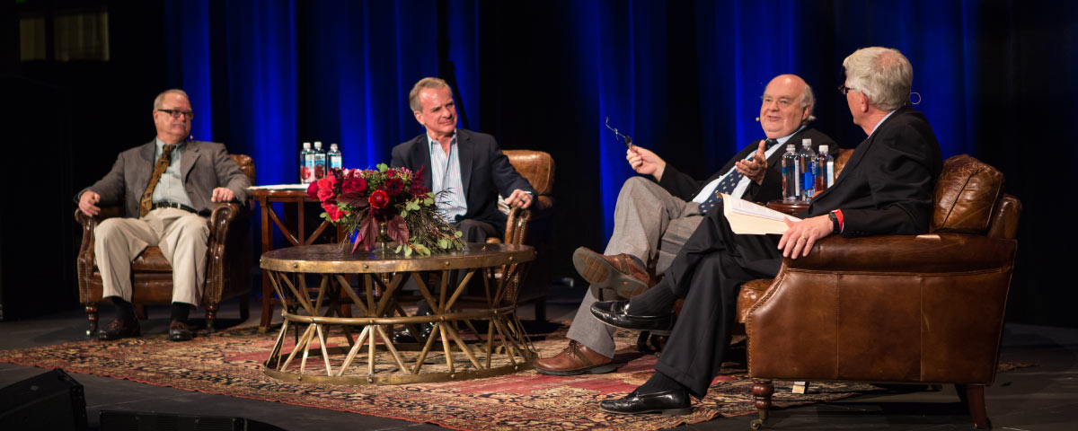 four men talking on a stage