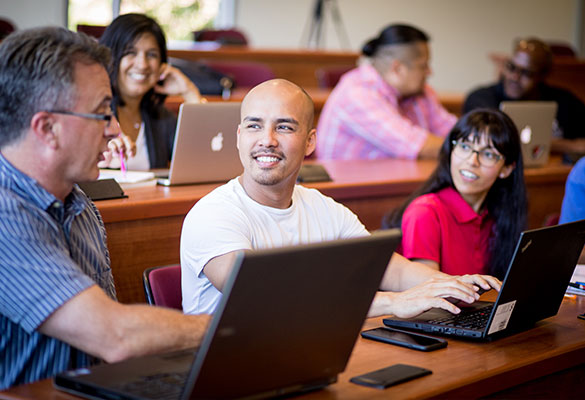 Students in a classroom smiling and talking with each other.