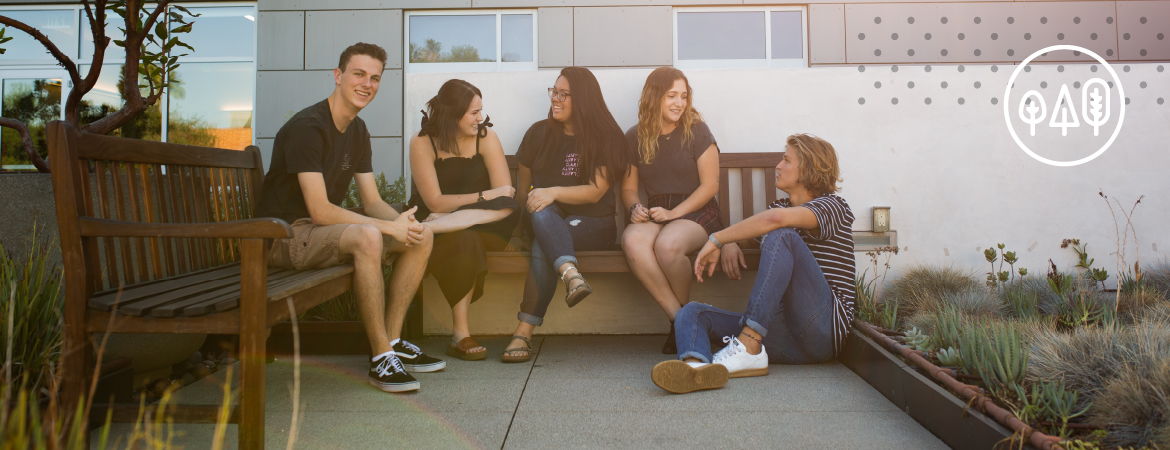 A group of students talking and laughing on a bench