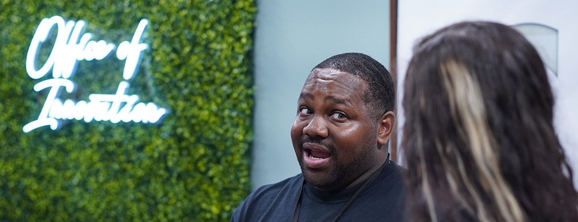 two students in front of office of innovation signage