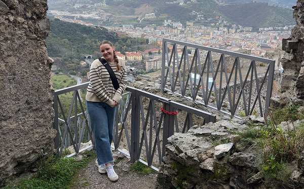 student posing in front of village