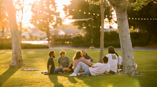 Students sitting on Sycamore Lawn at sunset