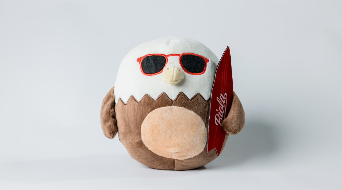 a plush eagle wearing sunglasses and holding a surfboard
