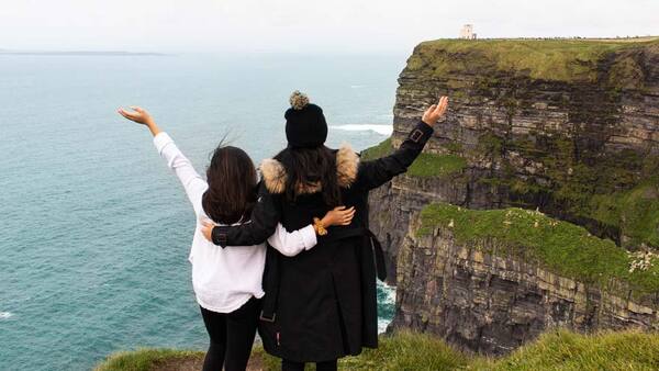 two women posing in front of cliffs overlooking the ocean