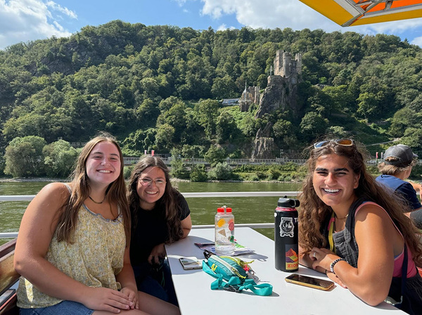 three students in front of a river