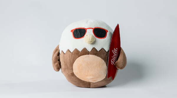 a plush eagle wearing sunglasses and holding a surfboard