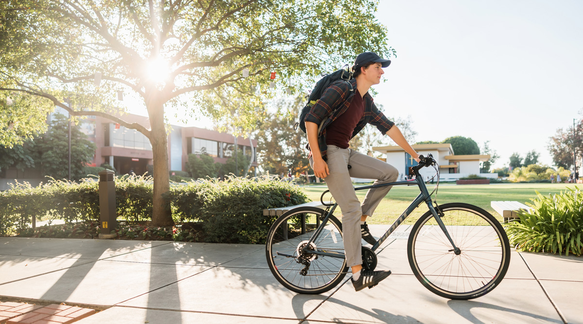 Student biking by Metzger Lawn