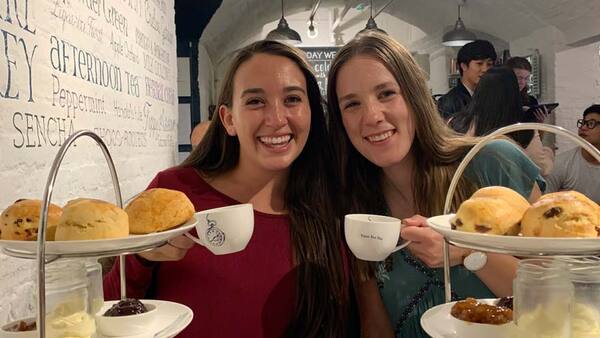 two young women smiling and holding tea cups