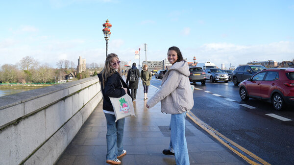 Two girls walking across a bridge smiling