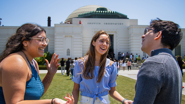 three students interacting in front of the observatory
