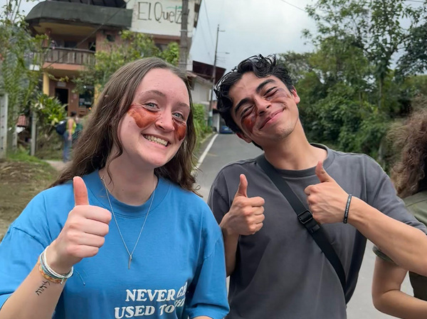 two students posing with their thumbs up