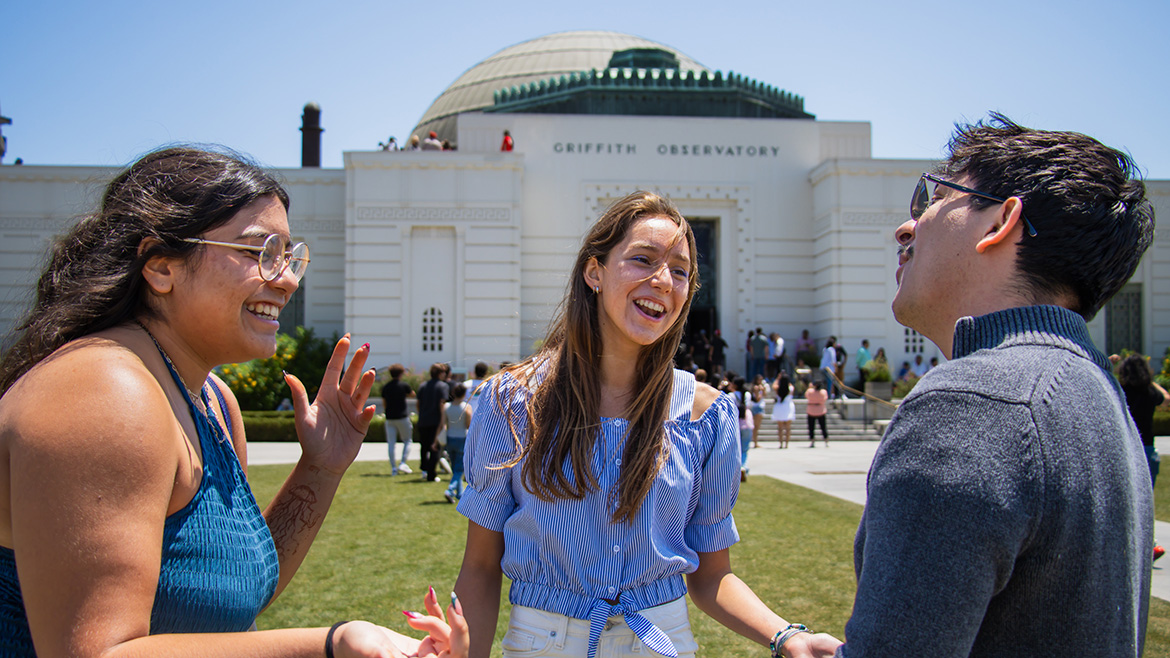 three students interacting in front of the observatory