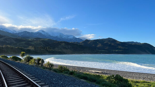 a rocky beach on a sunny day with mountains in the background